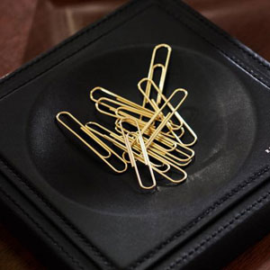 Manners Maketh Man and here is a quick escort ettiquette guide. A close up picture of gold paperclips in black leather holder. 